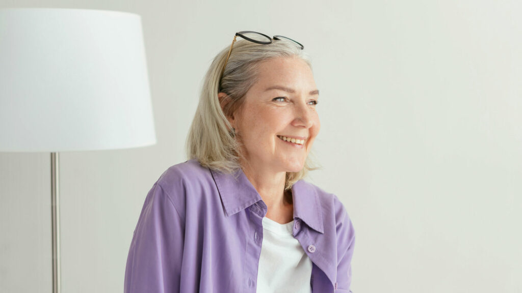 Elderly Woman Sitting In A Purple Shirt Smiling