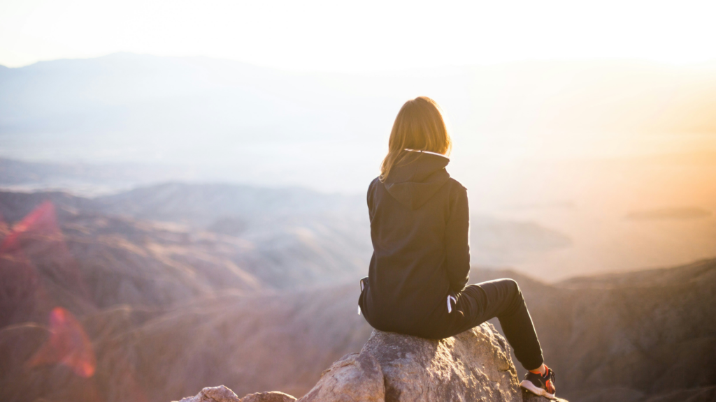 Woman Sitting On Top Of Mountain