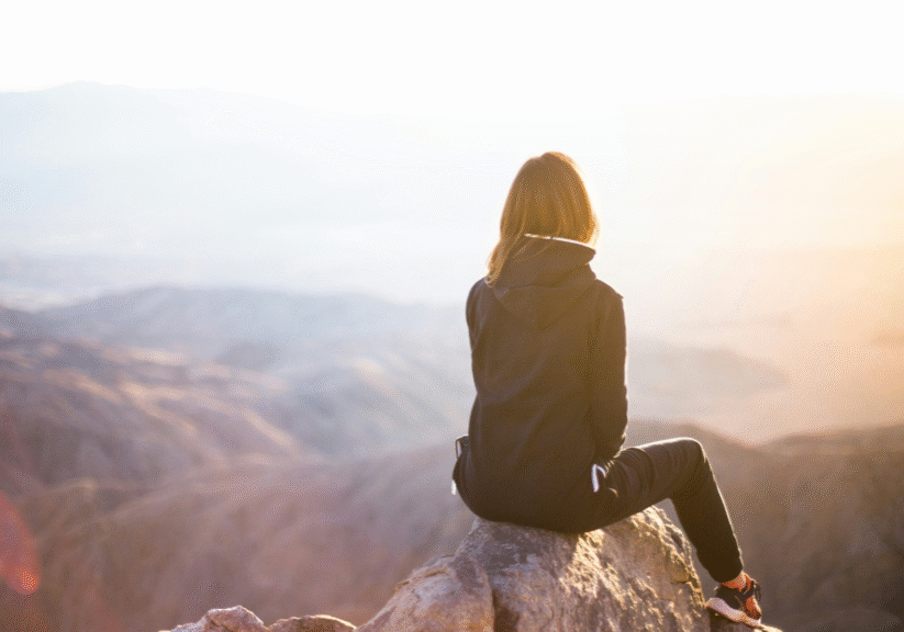 Woman Sitting On Top Of Mountain